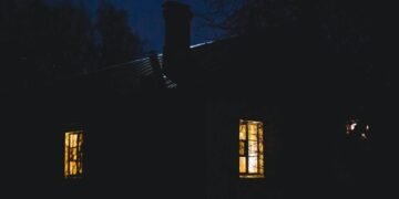 A tranquil rural house with glowing windows on a quiet night.